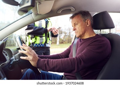 Male Driver Being Stopped By Female Traffic Police Officer With Digital Tablet For Driving Offence