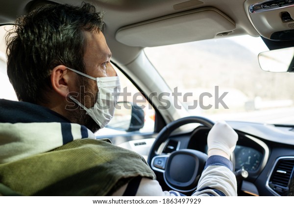 Male driver in car with\
mask
