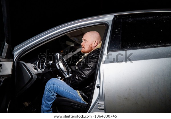 Male\
driver in a leather jacket smoking in the car in the dark time.\
Drunk driver in the car. Night unusual photo\
shoot.