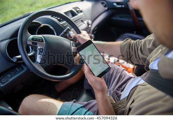 Male driver looking\
at map in smartphone