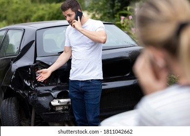 Male Driver On Phone Call To Insurance Company After Accident With Female Motorist - Shutterstock ID 1811042662