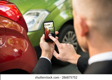 Männlicher Fahrer fotografiert mit seinem Handy nach Verkehrskollision