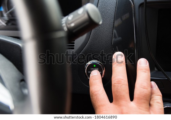 The\
male driver starts the engine of his car with keyless access\
system. The finger presses the engine start\
button.