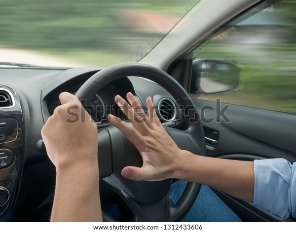 Male driver steering a car and\
press car horn, honking soung to warn other people in\
traffic