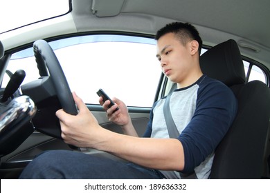 A Male Driver Texting On A Cellphone While Driving