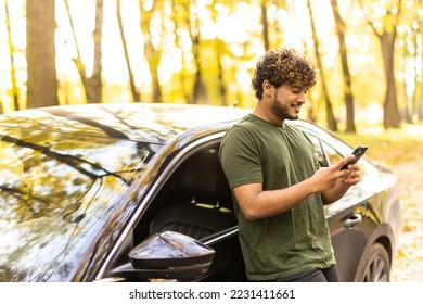 Male driver using a phone while standing near his car - Shutterstock ID 2231411661