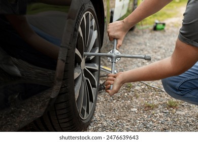 Male driver's hands with the key tightening the bolts on the wheel of his new car on road side - Powered by Shutterstock