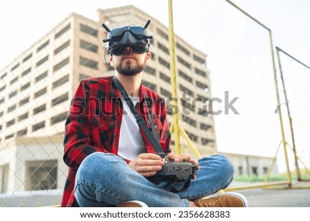 Male drone pilot operating fpv multicopter uisng goggles and remote controller for taking aerial urban photography and videography.