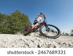 Male electric mountain bike rider going downhill and braking on a hilly rocky trail, low-angle shot. E-mountain biking concept.