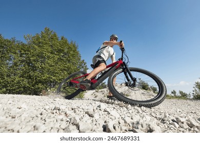 Male electric mountain bike rider going downhill and braking on a hilly rocky trail, low-angle shot. E-mountain biking concept. - Powered by Shutterstock