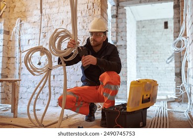 Male electrical contractor working with multiple cables during installation precess on construction site. - Powered by Shutterstock