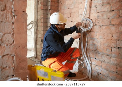 Male electrical contractor working with multiple cables during installation precess on construction site. - Powered by Shutterstock