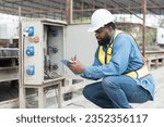 Male electrician engineer maintenance electric system at construction site work. African American male electrician engineer checking electric system at precast concrete wall construction site