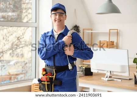 Male electrician with extension cord in room