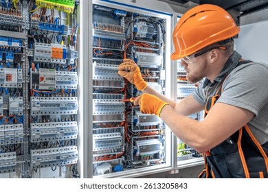Male electrician working in electrical panel. Male electrician in overalls.