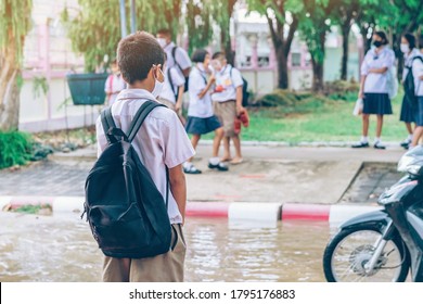 Male Elementary School Student Wear Face Mask To Prevent The Coronavirus(Covid-19) Wait For His Parents To Pick Him Up To Return Home After School And The Rain Just Stop In Front Of The School Gate