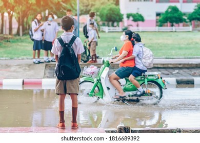 Male Elementary School Student Wear Face Mask To Prevent The Coronavirus(Covid-19) Wait For Her Parents To Pick Her Up To Return Home After School And The Rain Just Stop In Front Of The School Gate