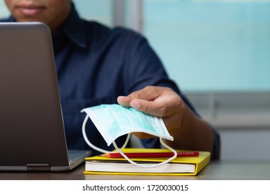 Male Employee And Heath Mask Reading Data From Computer Laptop While Working At Home To Win The Corona Virus, Covid-19.