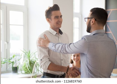 Male employer shaking hand of proud worker, congratulating with high work results or achievements, boss handshaking happy satisfied intern greeting with job promotion. Concept of rewarding