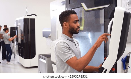 Male Engineer Or Apprentice Using CNC Machine In Factory