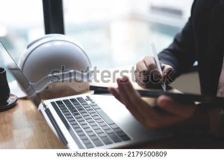 Male engineer or architecture man working with autocad program on digital tablet and laptop computer with blue print on office desk, close up