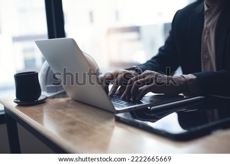 Male engineer or architecture man working with autocad program on laptop computer with digital tablet and blue print on office desk, close up