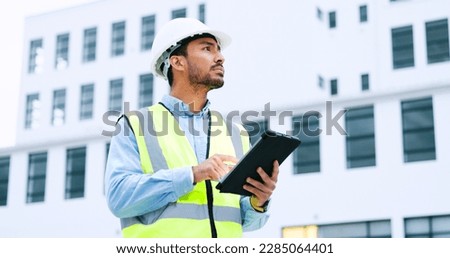Male engineer checking data on digital tablet and inspecting construction site. Technician in a hardhat doing management and project planning outdoors. Skilled worker looking or overseeing operations