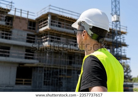 Male engineer at the construction site of a building during an inspection. Man supervisor, professional architect wearing hard hat safety helmet and reflective clothing vest.