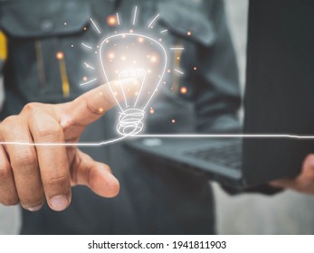 Male engineer is holding a notebook and pointing finger at a light bulb.idea concept. - Shutterstock ID 1941811903