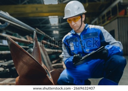 Male engineer inspecting Technical Control of cargo ship propeller at shipyard facility.