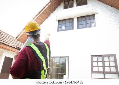 A male engineer inspects the house to deliver it to the customer. Standing in front of the house, pointing to the front. concept of house construction residential building