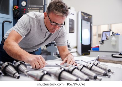 Male Engineer Measuring CAD Drawings In Factory