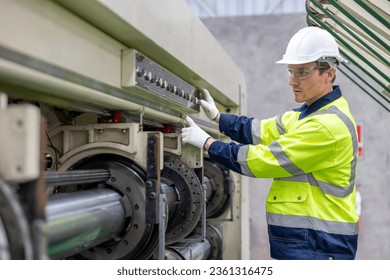 Male engineer paper cardbox factory in professional uniform check and analyse in paper industrial. Male factory worker use notebook testing program  in high teachnology paper production line. - Powered by Shutterstock