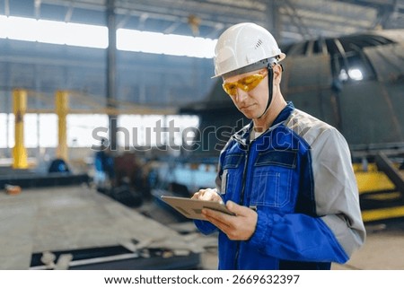 Male engineer in shipyard using tablet for cargo industry operations.