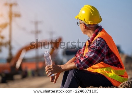 Male engineer takes a break to drink water to relax in the sweltering midday heat.