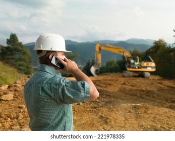 male engineer talking on the phone while supervising construction
