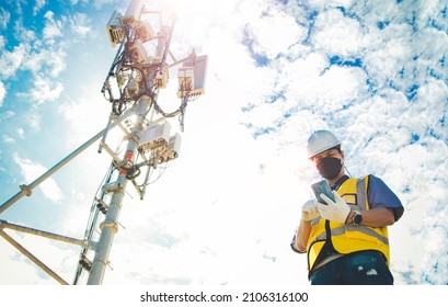 Male engineer uses a smartphone to connect to a 5G network,working in the field near a telecommunication tower that controls cellular electrical installations : Telecom modern communication technology - Shutterstock ID 2106316100