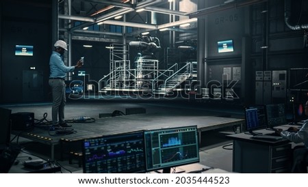 Male Engineer Uses Tablet Computer while Working in an Industial Facility at a Factory. Scientist uses Augmented Reality Software. Empty Space Left for Mock Up Template for VFX.