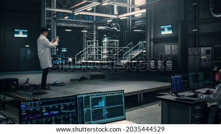 Male Engineer Uses Tablet Computer while Working in an Industial Facility at a Factory. Scientist uses Augmented Reality Software. Empty Space Left for Mock Up Template for VFX.