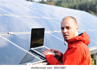 Male Engineer Using Laptop, Solar Panels In Background