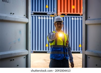 Male engineer wearing a safety suit and a helmet is holding a torch, he is open cargo container to inspect the cargo inside. Concept of industrial management services for import and export goods. - Powered by Shutterstock