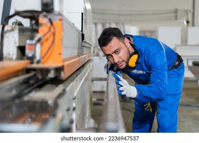 Male engineer worker checking conveyor belt machine at the industry factory. Male technician wear safety gloves and uniform working maintaining machine in the factory - Powered by Shutterstock