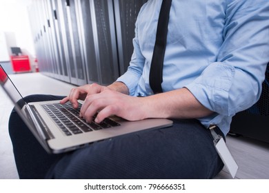 Male IT Engineer Working On A Laptop In Server Room At Modern Data Center