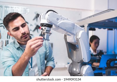 Male Engineers Maintenance Robot Arm At Lab. He Are In A High Tech Research Laboratory With Modern Equipment. Technology And Innovation Concept.