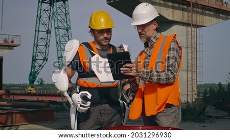 Male engineers using tablet on construction site together