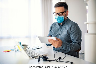 Male entrepreneur analyzing business reports while wearing face mask and working in the office during virus epidemic. Male employee wearing a health mask Preventing corona virus infection covid-19 - Powered by Shutterstock