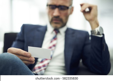 Male entrepreneur holding modern visit card with selective focus, made by creative web designers and marketing experts dealing with brand building strategies to attract customers to product, services 