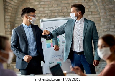 Male Entrepreneurs With Protective Face Masks Elbow Bumping While Greeting On A Business Meeting In The Office., 