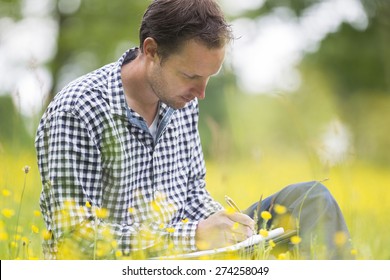 Male Environmentalist Writing On Notepad While Sitting In Park