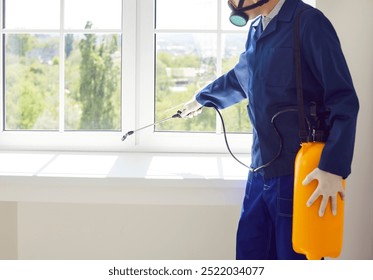 Male exterminator from pest control service wearing protective safety mask and blue workwear suit working inside house spraying toxic liquid or gas from yellow sprayer bottle over white window sill - Powered by Shutterstock